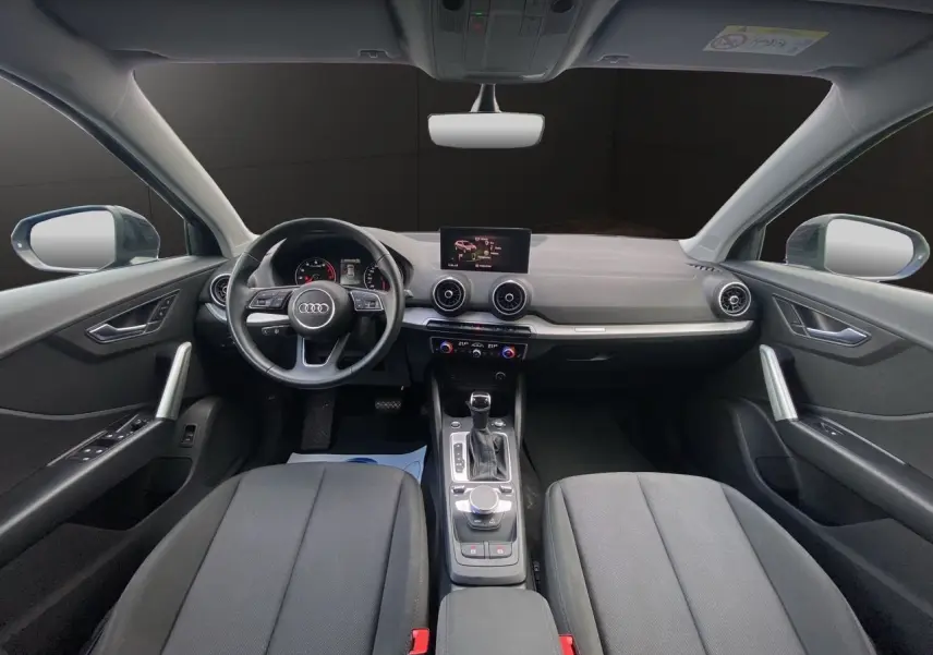 Vue intérieure avant de l'Audi Q2 35 TFSI S-Line 2023 avec tableau de bord noir et écran central GPS.