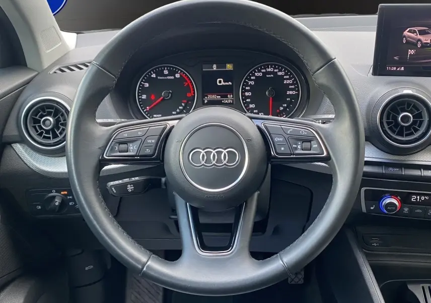 Vue centrée sur le volant noir de l'Audi Q2 2023 avec tableau de bord digital et commandes multifonctions visibles