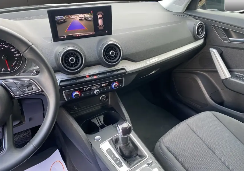 Vue intérieure de l'Audi Q2 35 TFSI 2023 montrant le tableau de bord noir avec écran caméra de recul et console centrale.