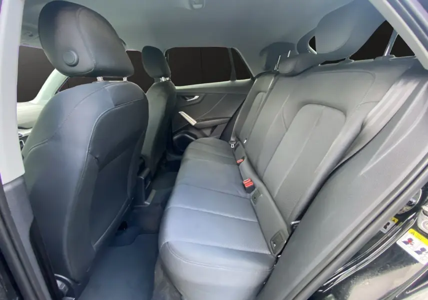 Vue intérieure arrière droite de l'Audi Q2 2023 avec sièges tissu noir et appuie-têtes intégrés.
