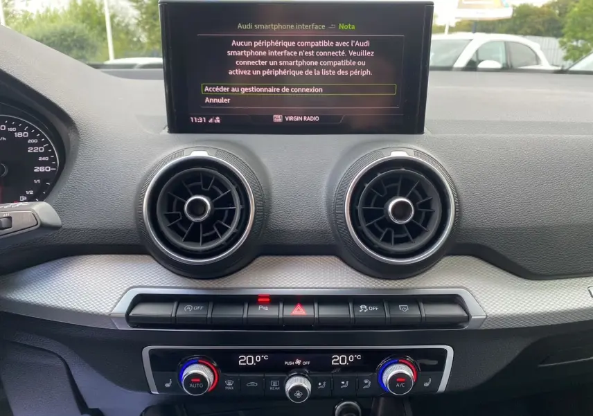 Tableau de bord de l'Audi Q2 noir Mito 2023, vue frontale centrée sur l'écran MMI et les aérateurs ronds.
