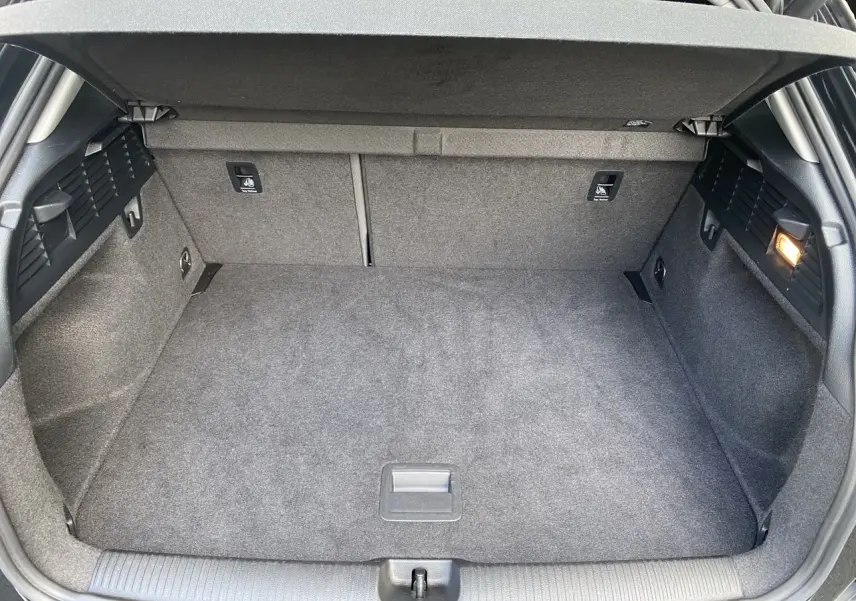 Coffre spacieux et propre de l'Audi Q2 noir mito, vue intérieure arrière avec éclairage latéral allumé.