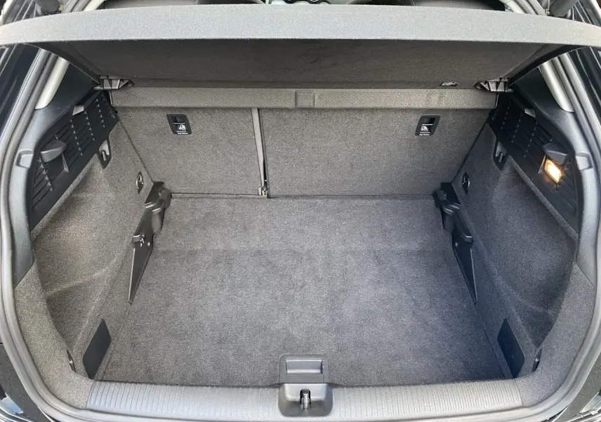 Coffre spacieux de l'Audi Q2 noir mito, vue intérieure arrière avec revêtement gris et éclairage latéral allumé.