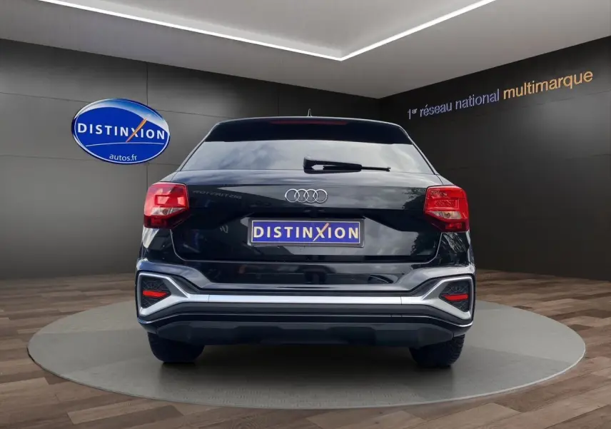 Vue arrière d'un Audi Q2 noir Mito avec hayon motorisé et feux arrière LED dans un showroom.