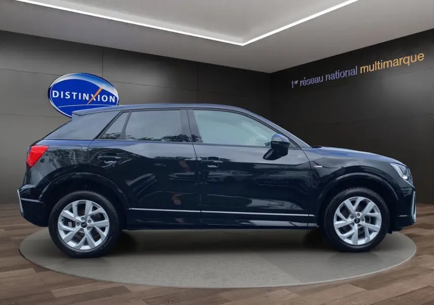 Profil côté gauche d'un Audi Q2 noir mito 2023 avec jantes alliage 17 pouces et hayon motorisé visible en showroom.