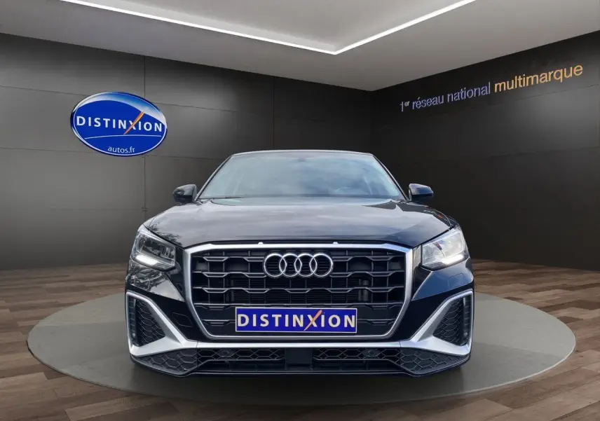 Vue frontale d'un Audi Q2 noir Mito avec calandre hexagonale et éclairage LED dans un showroom.
