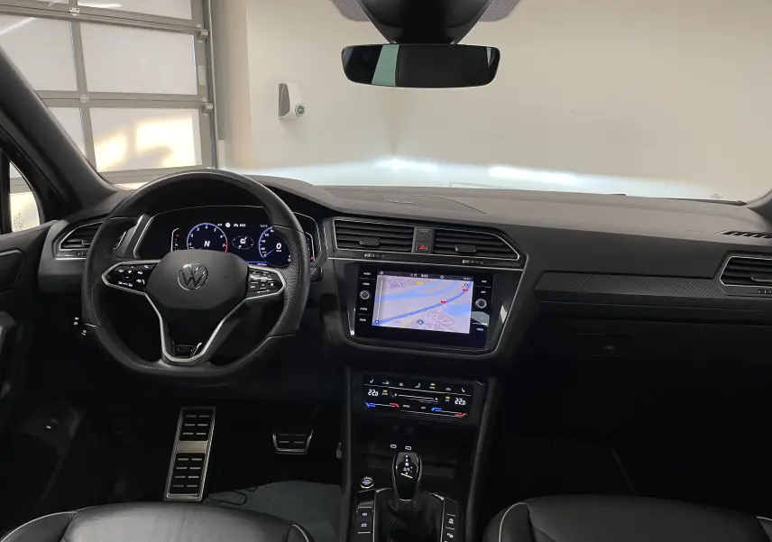 Vue intérieure avant du Volkswagen Tiguan 2024 avec tableau de bord noir, écran tactile et volant multifonction.