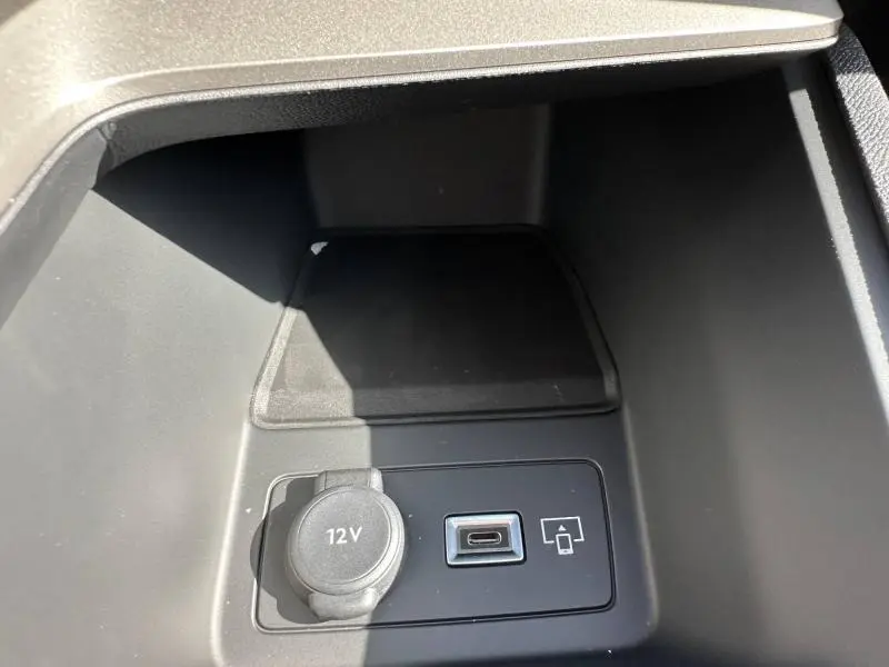 Gros plan sur la prise 12V et port USB-C dans le rangement central avant de la Peugeot 308 bleu 2025.