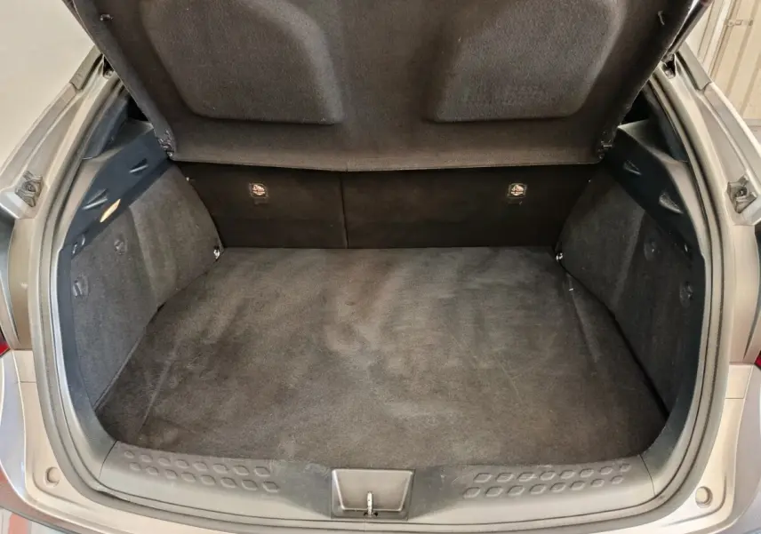 Coffre ouvert vu de dessus d’un Toyota C-HR gris clair, montrant l’espace de chargement vide et la garniture intérieure.