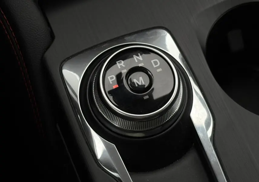 Gros plan sur le sélecteur rotatif de boîte automatique noir et chrome dans l’habitacle du Ford Kuga gris graphite.