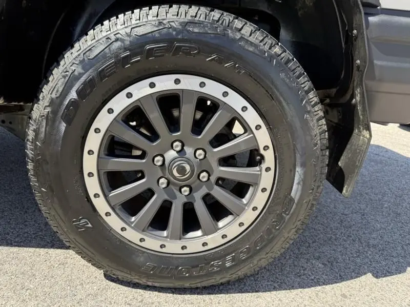 Gros plan sur la roue avant droite de l'INEOS Grenadier beige 2024 avec jante alliage et pneu Bridgestone Dueler.