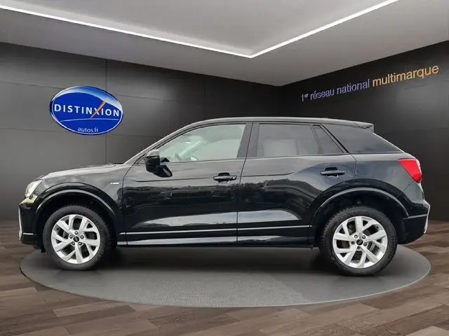 Audi Q2 noir mito vue de profil côté gauche, jantes alliage 17 pouces, sur fond intérieur showroom