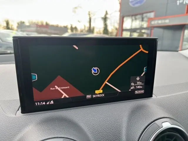 Écran GPS intégré sur le tableau de bord d'un Audi Q2 noir Mito, affichant une carte de navigation en extérieur.