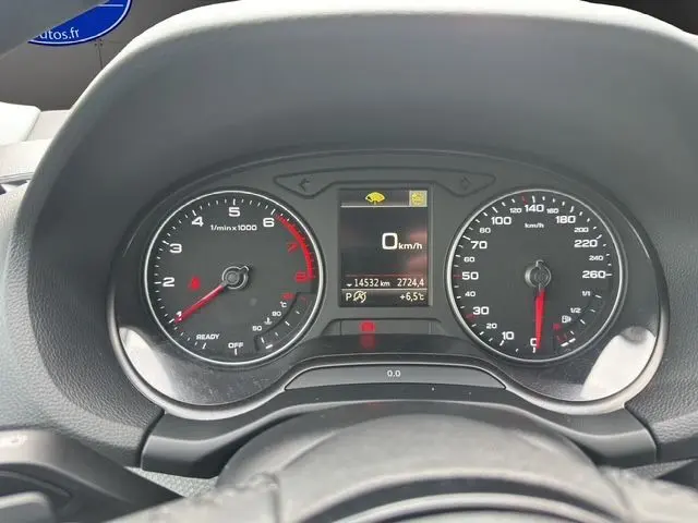Tableau de bord noir de l'Audi Q2 35 TFSI 2023 avec compte-tours, compteur vitesse et écran central digital.