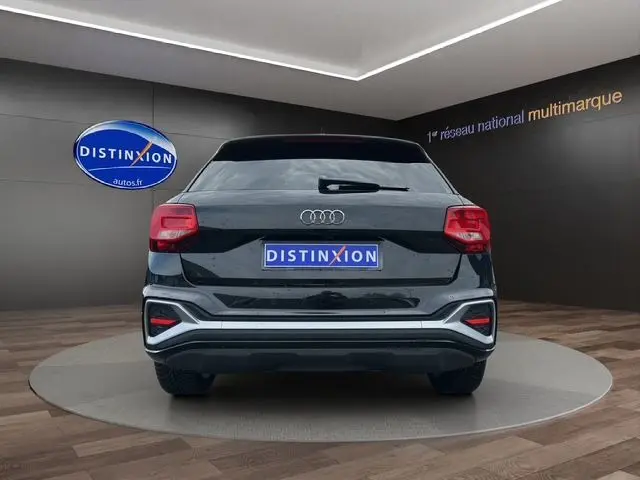 Vue arrière d'un Audi Q2 noir Mito 2023 avec feux LED et hayon motorisé dans un showroom.