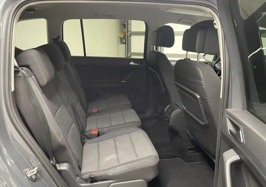 Vue intérieure côté gauche sur la banquette arrière grise du Volkswagen Touran 2024 avec sièges tissu et porte ouvert