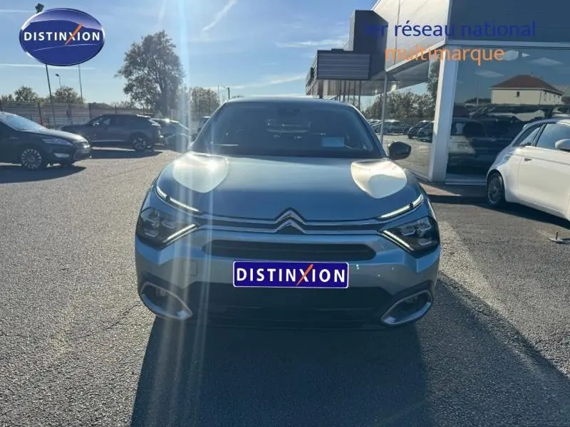 Vue frontale d'une Citroën C4 gris 2024 avec calandre distinctive et logo double chevron visible au soleil.