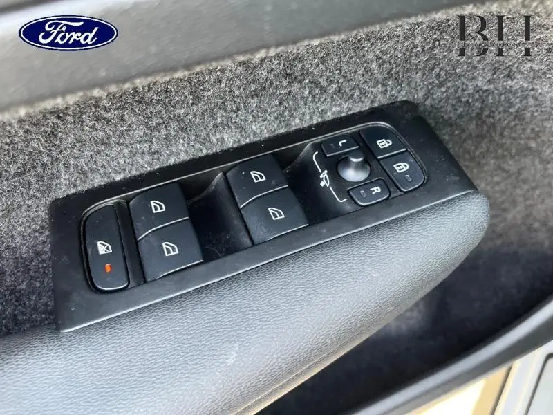 Gros plan sur les commandes des vitres électriques et rétroviseurs sur la porte côté conducteur d’un Volvo XC40 gris Glacier.
