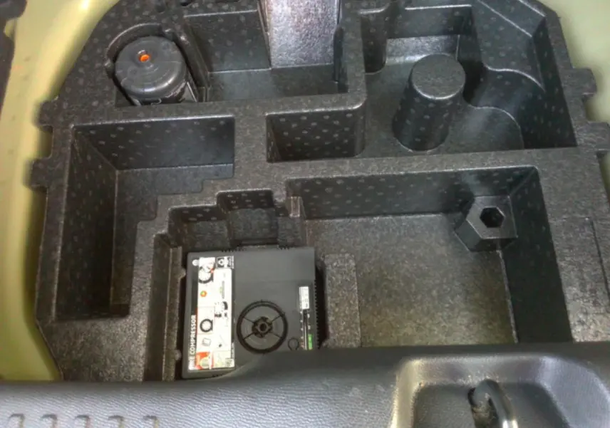 Vue en plongée sur le compartiment de rangement noir sous le coffre de la Citroën C3 gris foncé 2025.