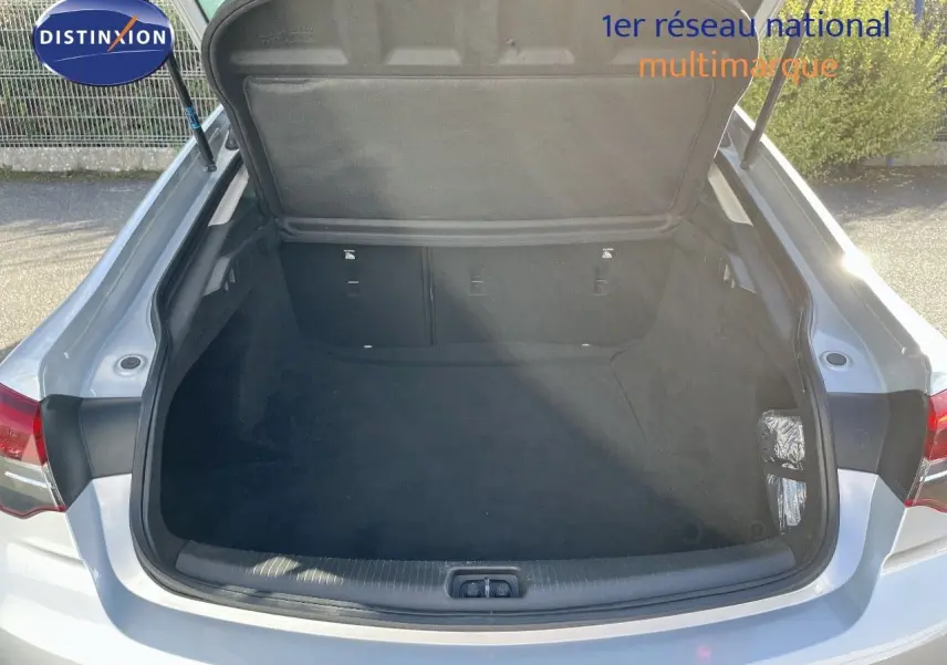 Coffre ouvert vu de l'arrière d'une Opel Insignia gris minéral métal, montrant un espace de chargement vide et propre.