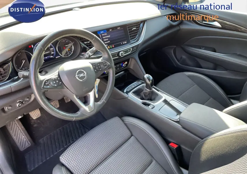 Vue intérieure côté conducteur de l'Opel Insignia 2.0D gris minéral, avec volant cuir, tableau de bord digital et boîte manuelle.