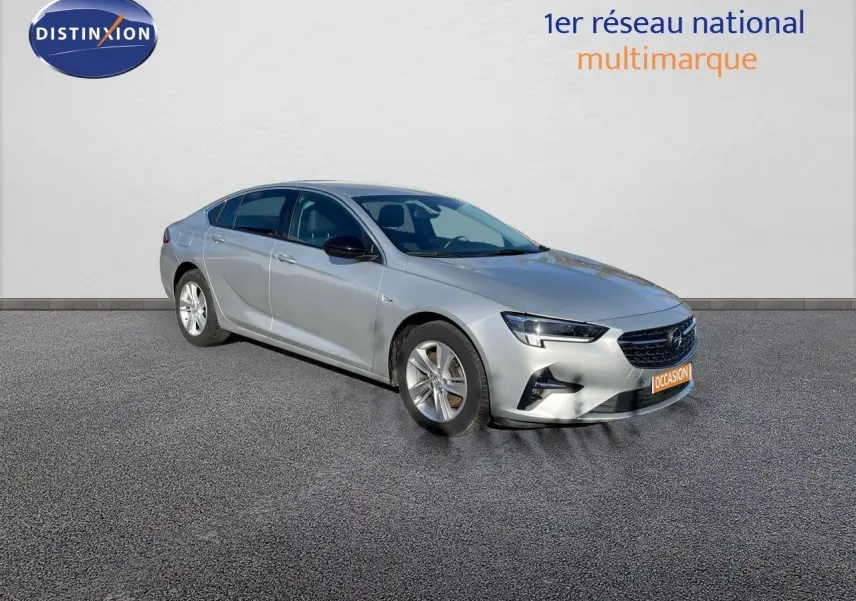 Opel Insignia gris minéral métal vue 3/4 avant droit, avec calandre noire et jantes argentées.