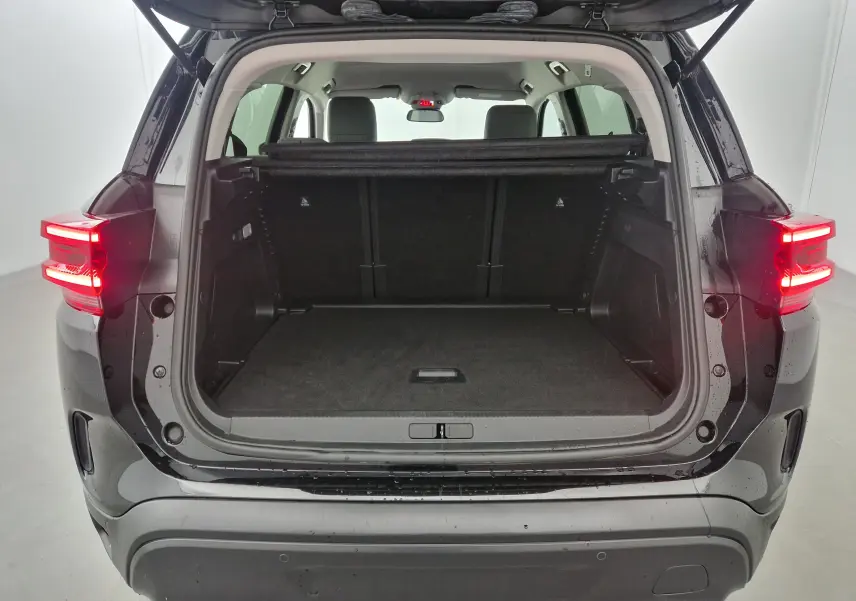 Coffre ouvert vu de l'arrière d'un Citroën C5 Aircross noir 2024 avec feux arrière allumés et intérieur spacieux.