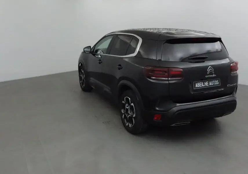 Vue 3/4 arrière droite d'un Citroën C5 Aircross noir 2024 avec vitres teintées et jantes originales.