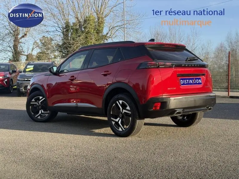 Peugeot 2008 rouge Elixir vue 3/4 arrière droit, jantes alu noires et toit noir contrasté, stationné en extérieur.