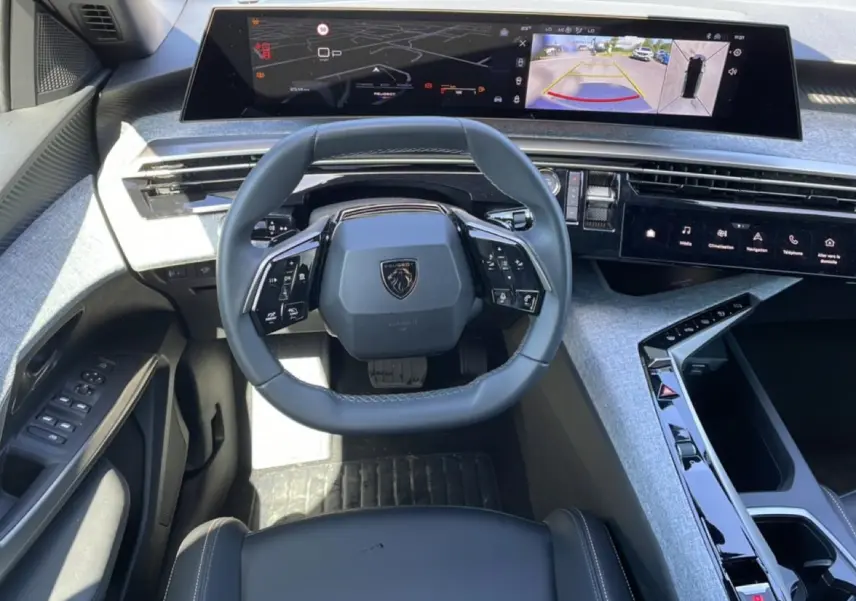 Vue intérieure du tableau de bord du Peugeot 5008 Hybrid 145 allure e-dcs6 2025 avec volant cuir et écrans numériques larges.