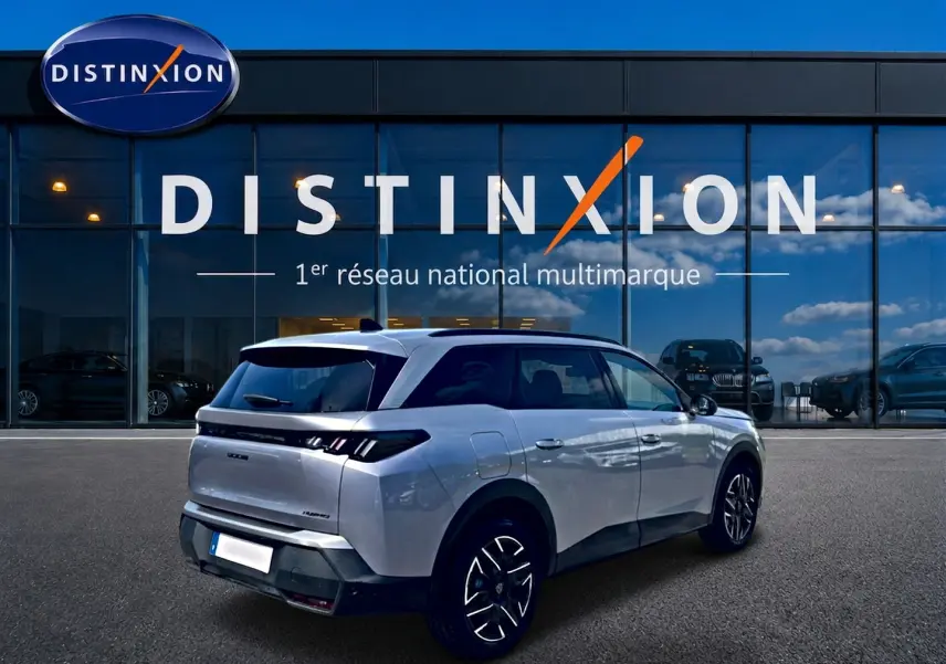 Peugeot 5008 Hybrid 145 allure e-dcs6 gris artense en 3/4 arrière droit devant une vitrine Distinxion.