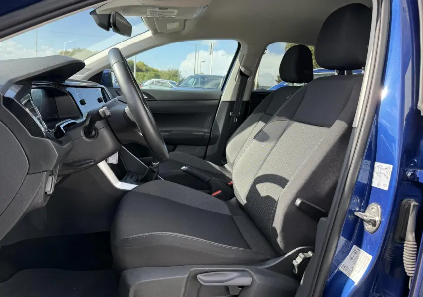 Intérieur côté conducteur du Volkswagen Taigo bleu récif 2024, sièges tissu noirs et tableau de bord moderne.