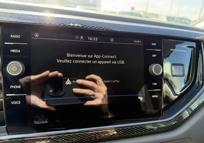 Écran tactile central du Volkswagen Taigo 2024 affichant App-Connect avec commandes autour en finition noire brillante.