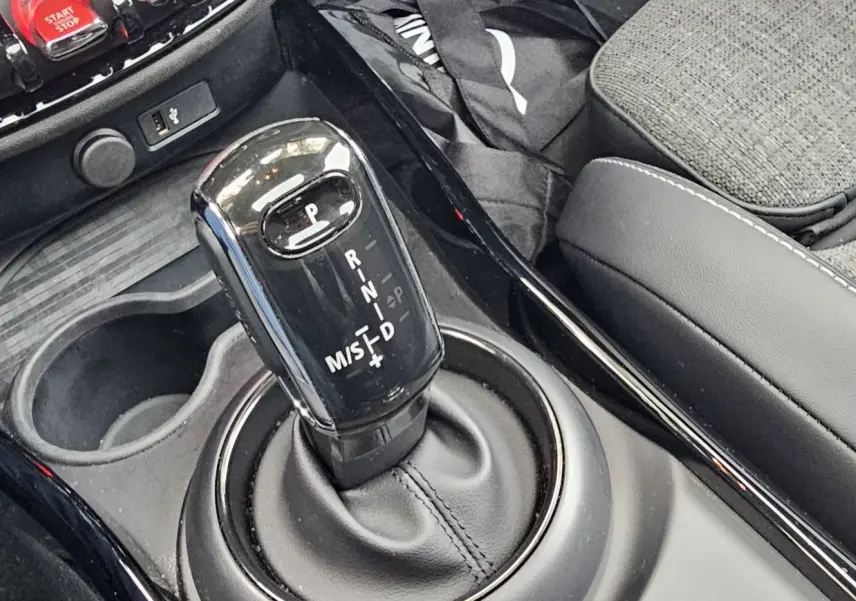 Le levier de vitesses automatique noir brillant de la MINI Cooper S Clubman 2022, entouré de la console centrale et siège gris.