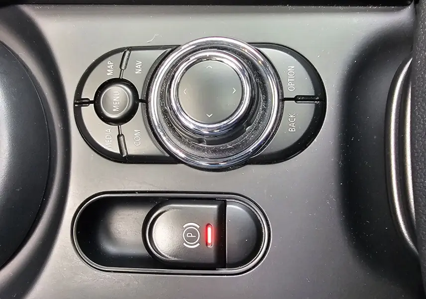 Gros plan sur la molette de commande multimédia et le frein à main électronique rouge dans l'habitacle noir de la MINI Cooper S Clubman 2022.