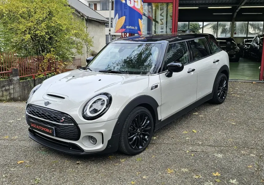 MINI Cooper S Clubman grise vue 3/4 avant droit avec toit noir et jantes noires brillantes stationnée devant un garage.