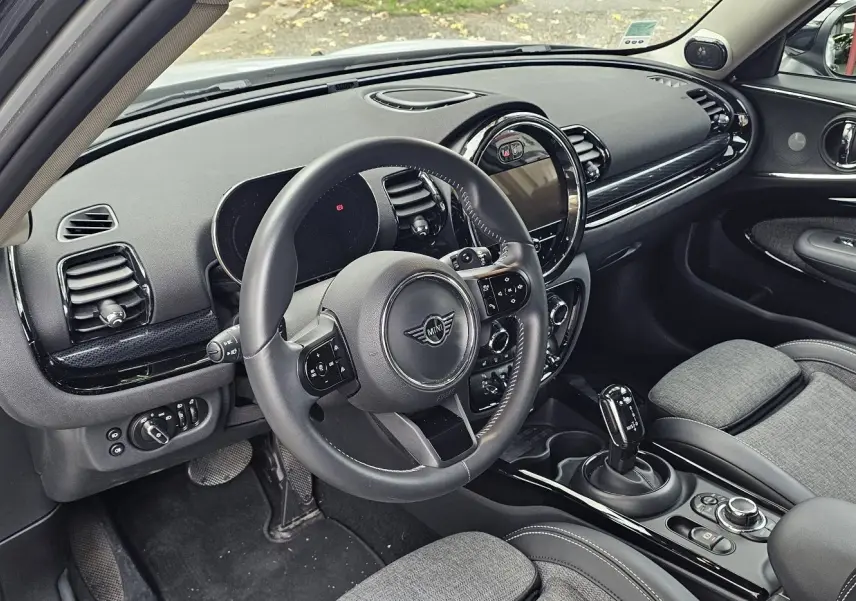 Intérieur côté conducteur d'une MINI Clubman grise 2022, avec tableau de bord noir et sellerie tissu gris.
