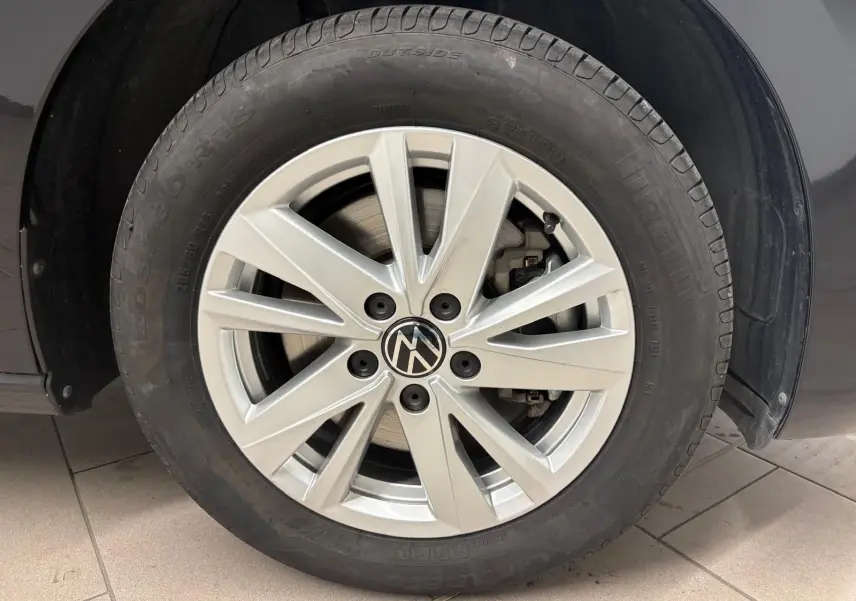 Gros plan sur la roue avant droite d'un Volkswagen Touran noir intense nacré avec jante alliage argentée.