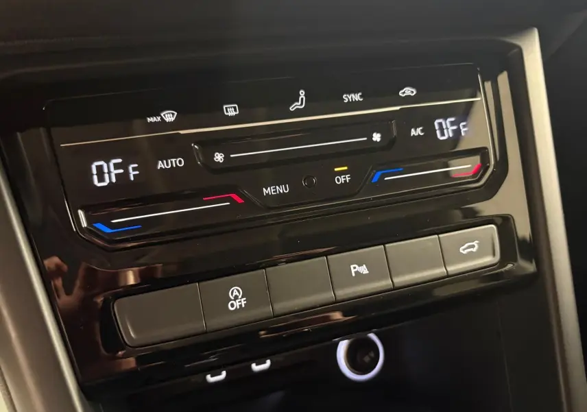 Panneau de commande de climatisation et boutons fonctionnels dans l'habitacle d'un Volkswagen Touran noir intense nacré.