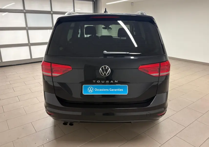 Vue arrière d'un Volkswagen Touran 2024 noir intense nacré, avec hayon électrique et badge Touran bien visible.