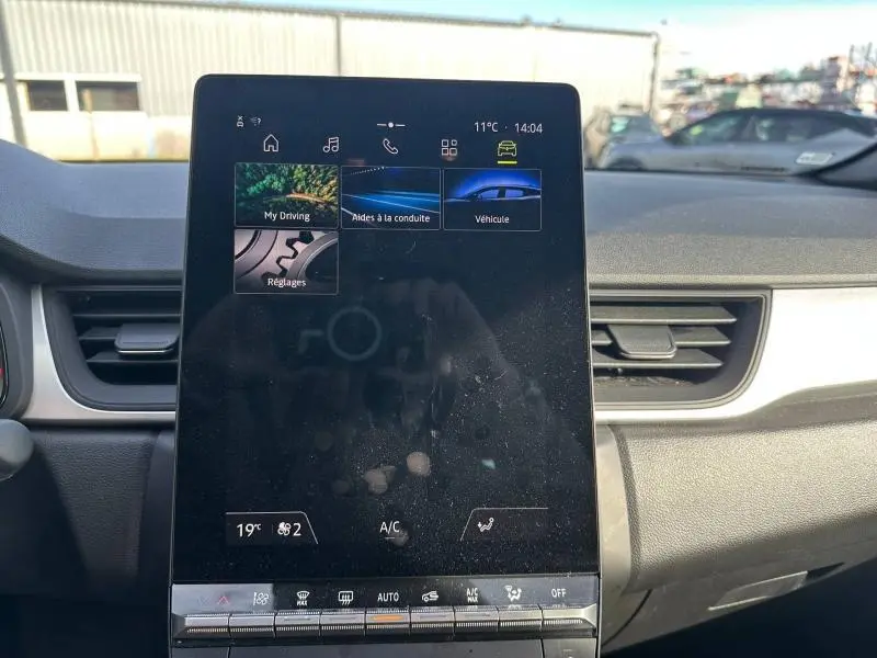 Vue intérieure centrée sur l'écran tactile du tableau de bord du Renault Captur blanc nacré 2025.