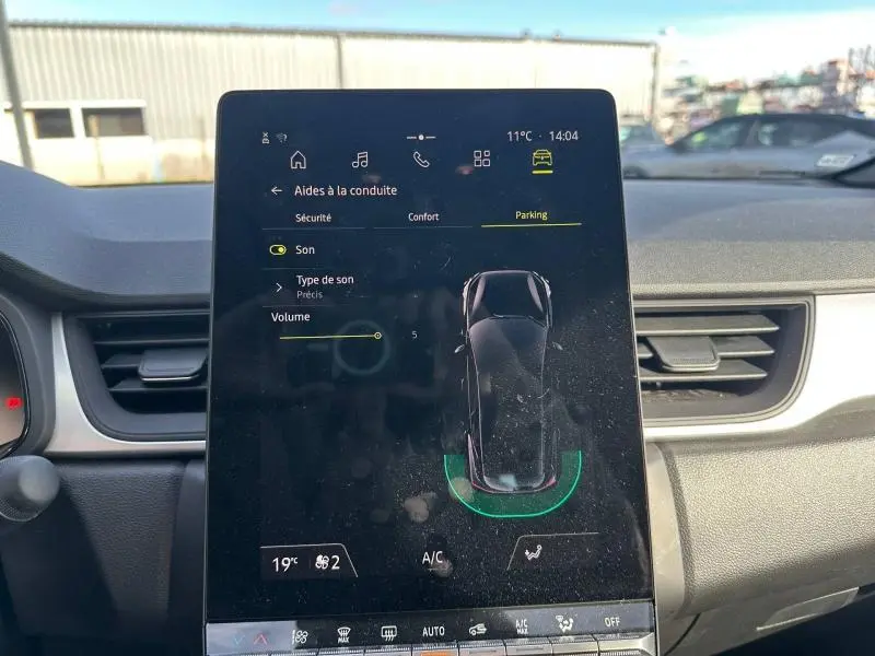 Écran tactile central du Renault Captur 2025 montrant l'aide au stationnement, intérieur noir avec tableau de bord gris.