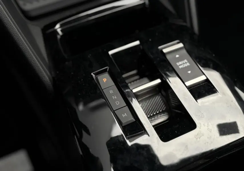 Gros plan sur la console centrale noire brillante de la Citroën C4 Hybrid avec commandes de boîte auto et mode de conduite.