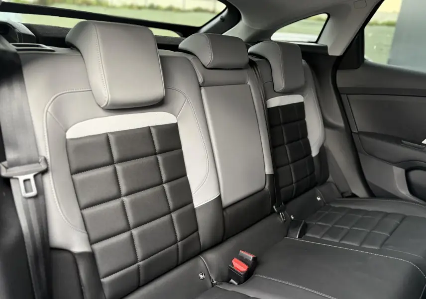 Vue intérieure arrière de la banquette bicolore noire et gris clair de la Citroën C4 Hybrid 2025 avec appuie-têtes intégrés.