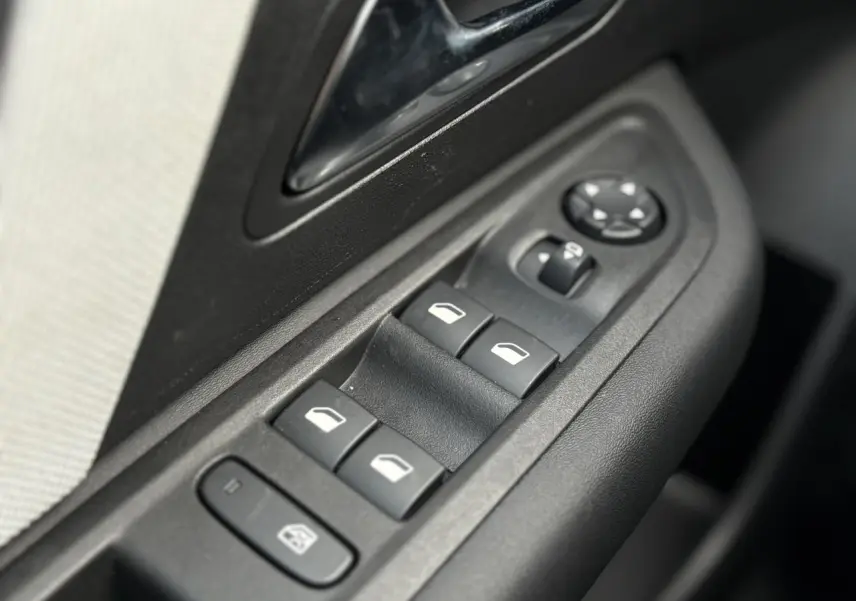 Gros plan sur les commandes des vitres électriques et rétroviseurs côté conducteur d'une Citroën C4 Hybrid gris Mercury.