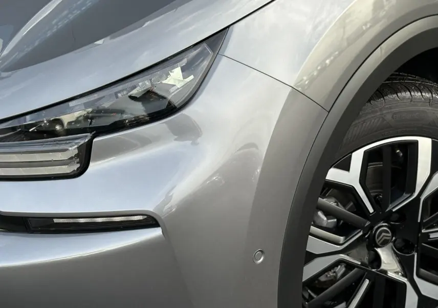 Gros plan sur l'avant droit gris Mercury du Citroën C4 Hybrid 2025 avec phare LED et jante alliage diamantée.