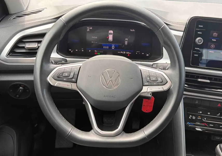 Vue intérieure centrée sur le volant cuir multifonctions du Volkswagen T-Roc 2025 avec tableau de bord digital et écran tactile.