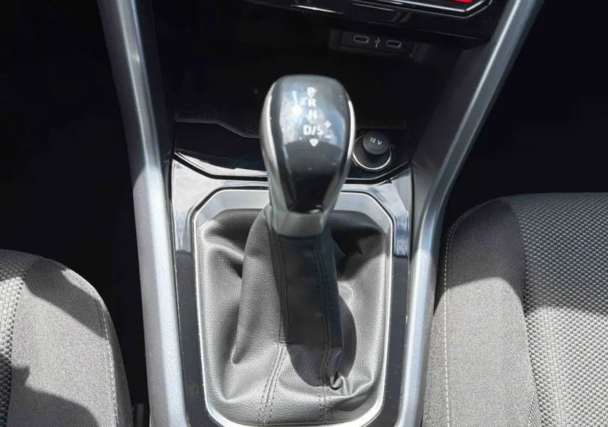 Gros plan sur le levier de vitesse DSG7 noir du Volkswagen T-Roc 2025, entouré de la console centrale et sièges gris.