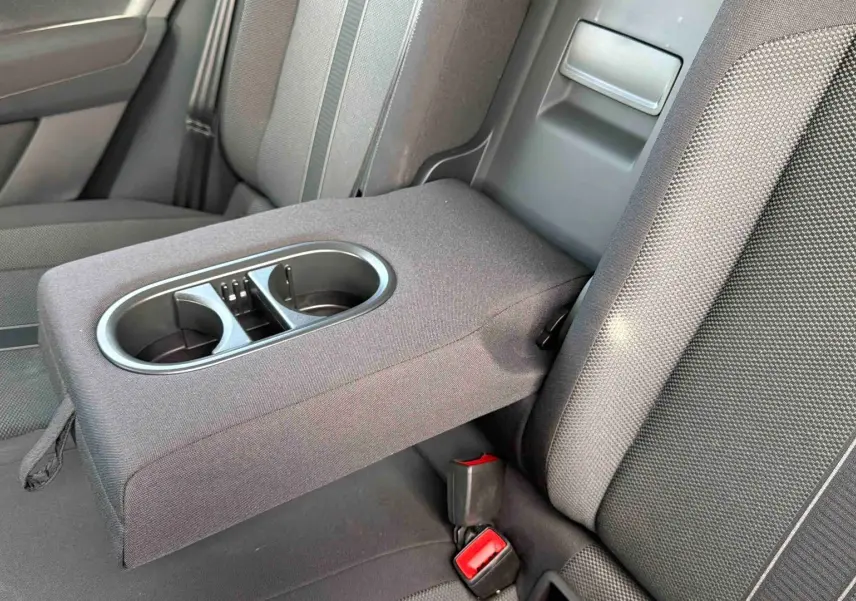 Vue rapprochée de l'accoudoir central arrière avec porte-gobelets sur les sièges tissu gris du Volkswagen T-Roc noir.