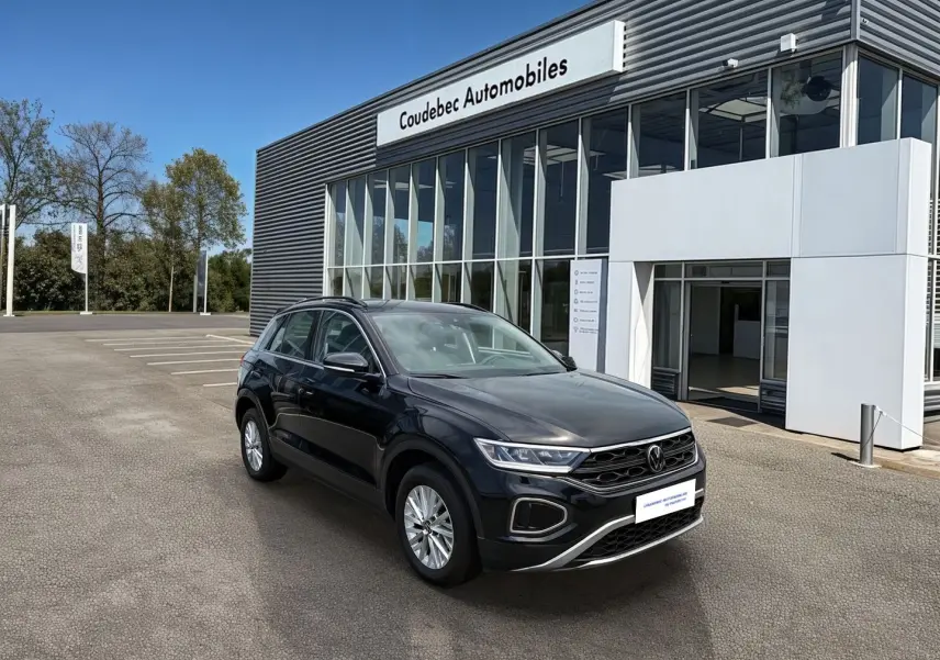 Volkswagen T-Roc noir vue 3/4 avant droit, avec jantes alliage 16'' et calandre distinctive, devant un concessionnaire.
